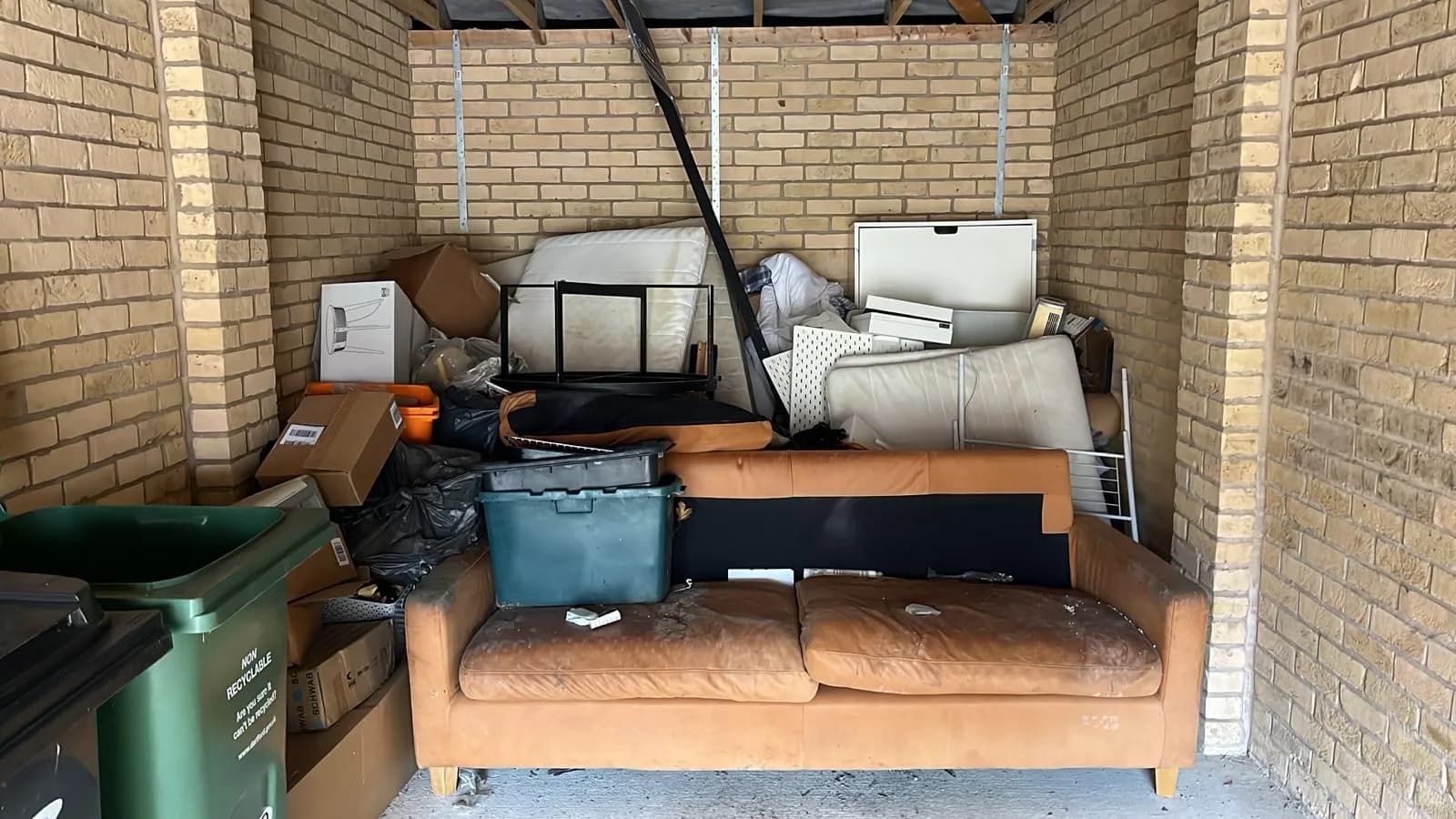 Gravesend garage before clearance — full of sofas, mattresses, boxes and old appliances