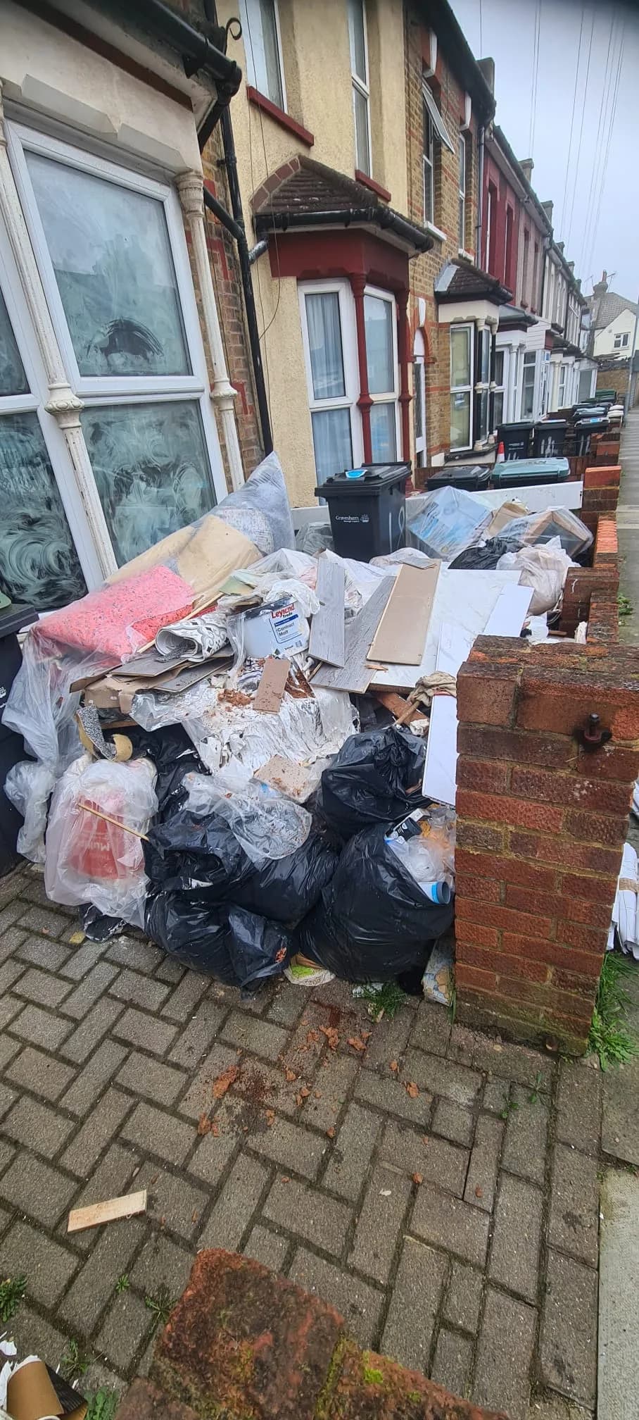 Large house clearance pile in Gravesend — bags, cardboard and furniture outside a Victorian terrace