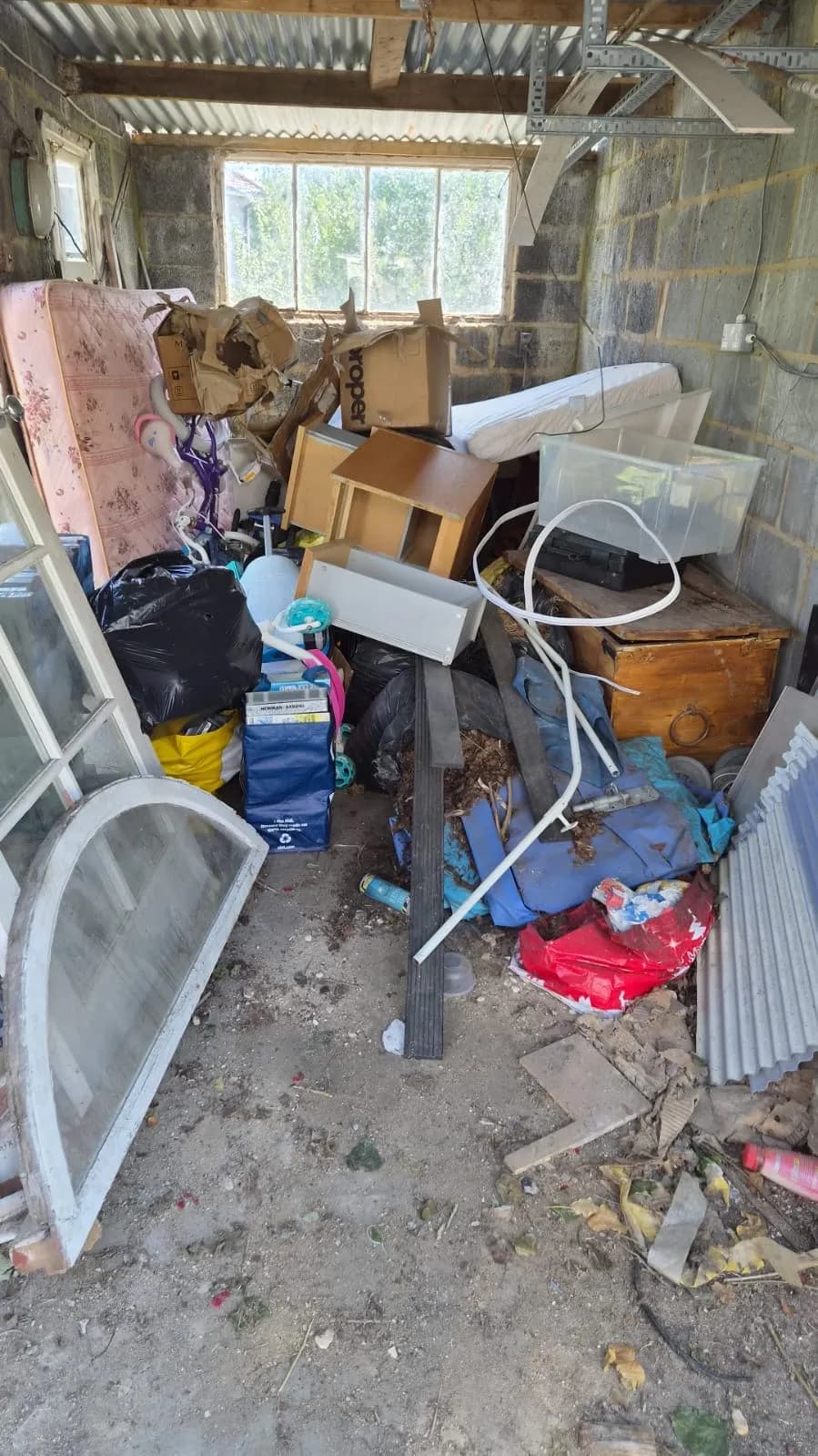 A garage in Northfleet packed to the roof with an old mattress, boxes, bags and furniture before Andy cleared it