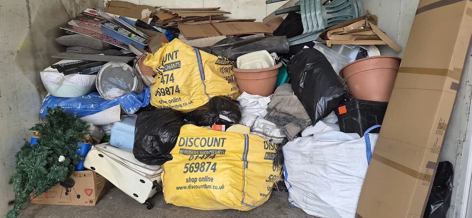 A garage in Gravesend packed to the roof with builders' bags, garden chairs, plant pots, a Christmas tree, a suitcase and boxes before clearance