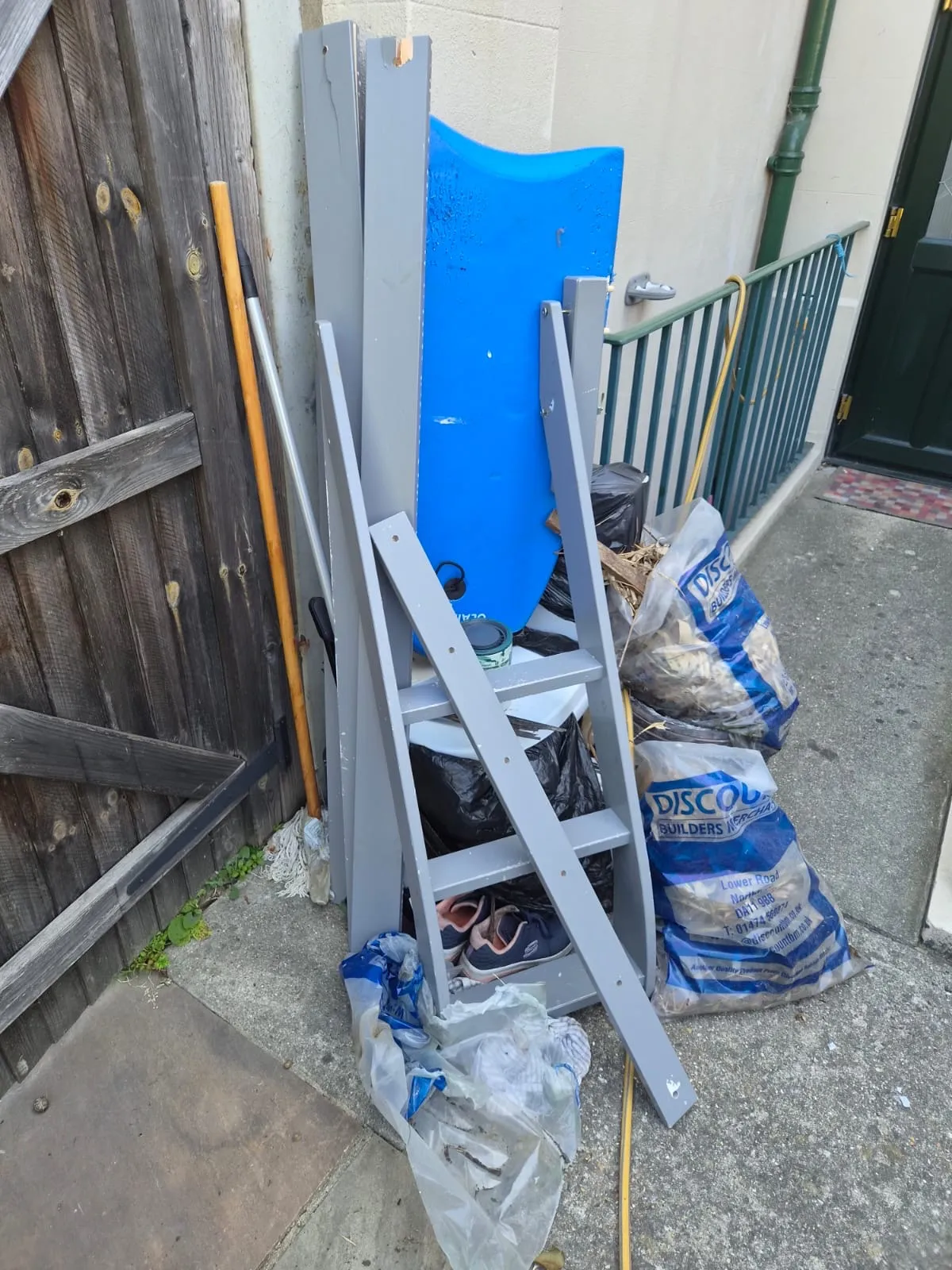 The side passage of a flat in Northfleet piled with old shelving, wardrobe panels, rubble sacks and bags before Andy cleared it