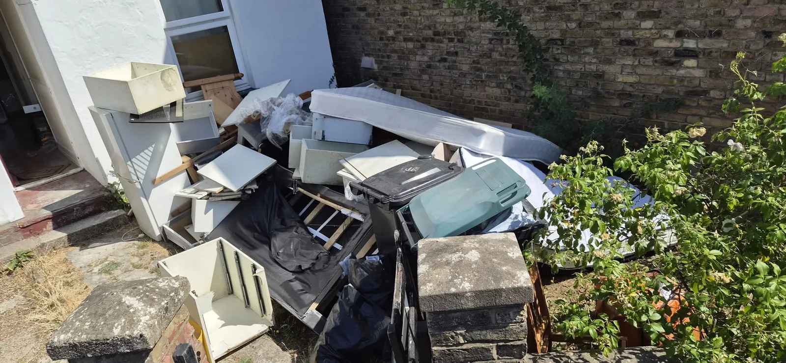 Mattress, bed base, wardrobe and drawers piled outside a white house in Gravesend before a full house clearance