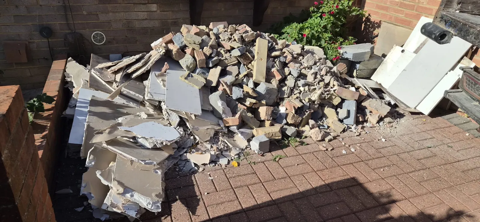 A pile of bricks, breeze blocks and broken plasterboard on a block-paved patio in Gravesend before removal