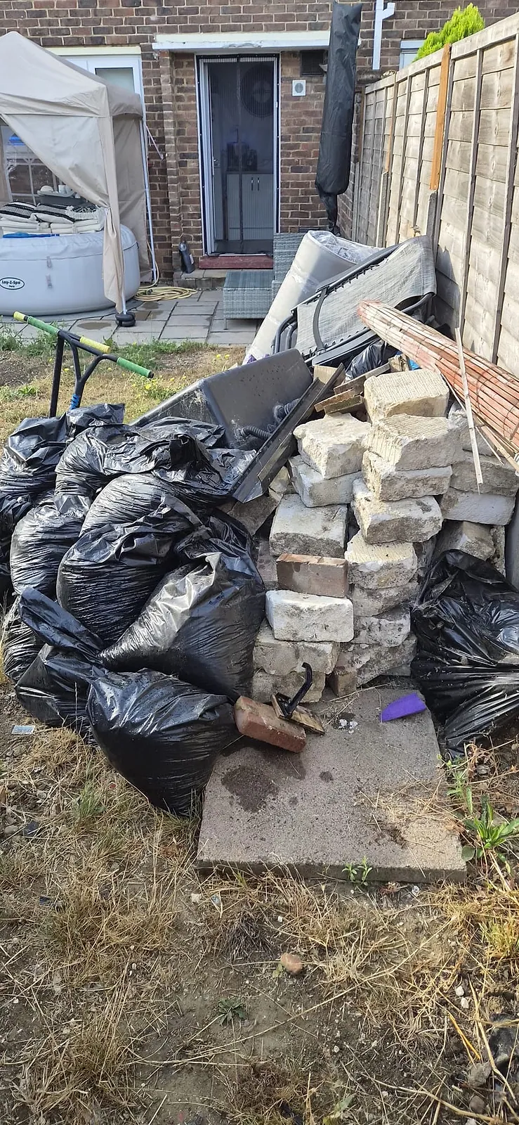 A dozen black rubbish bags, a stack of concrete blocks and an old sun lounger piled beside a hot tub in a Gravesend back garden