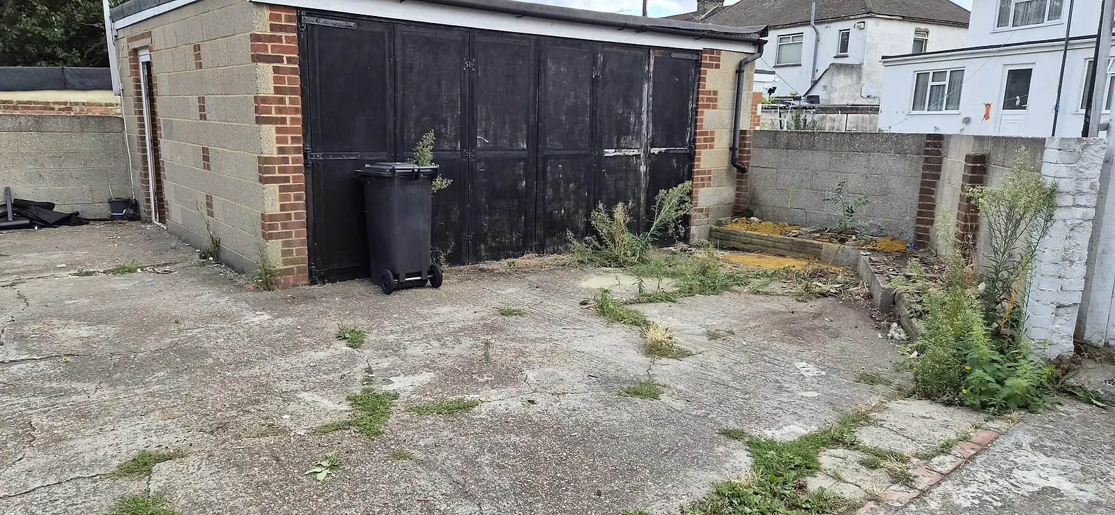 The same yard in front of the garage in Gravesend cleared, only the wheelie bin and a few weeds left